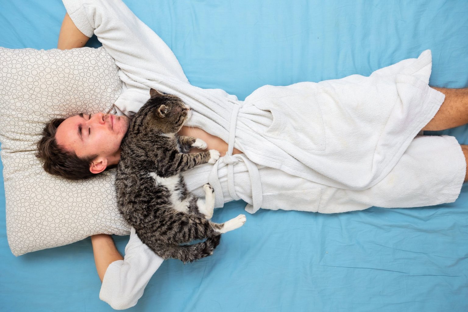 Homme qui fait une sieste paisible avec son chat endormi sur lui